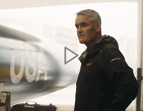 Russell Coutts standing next to a Sailgp boat