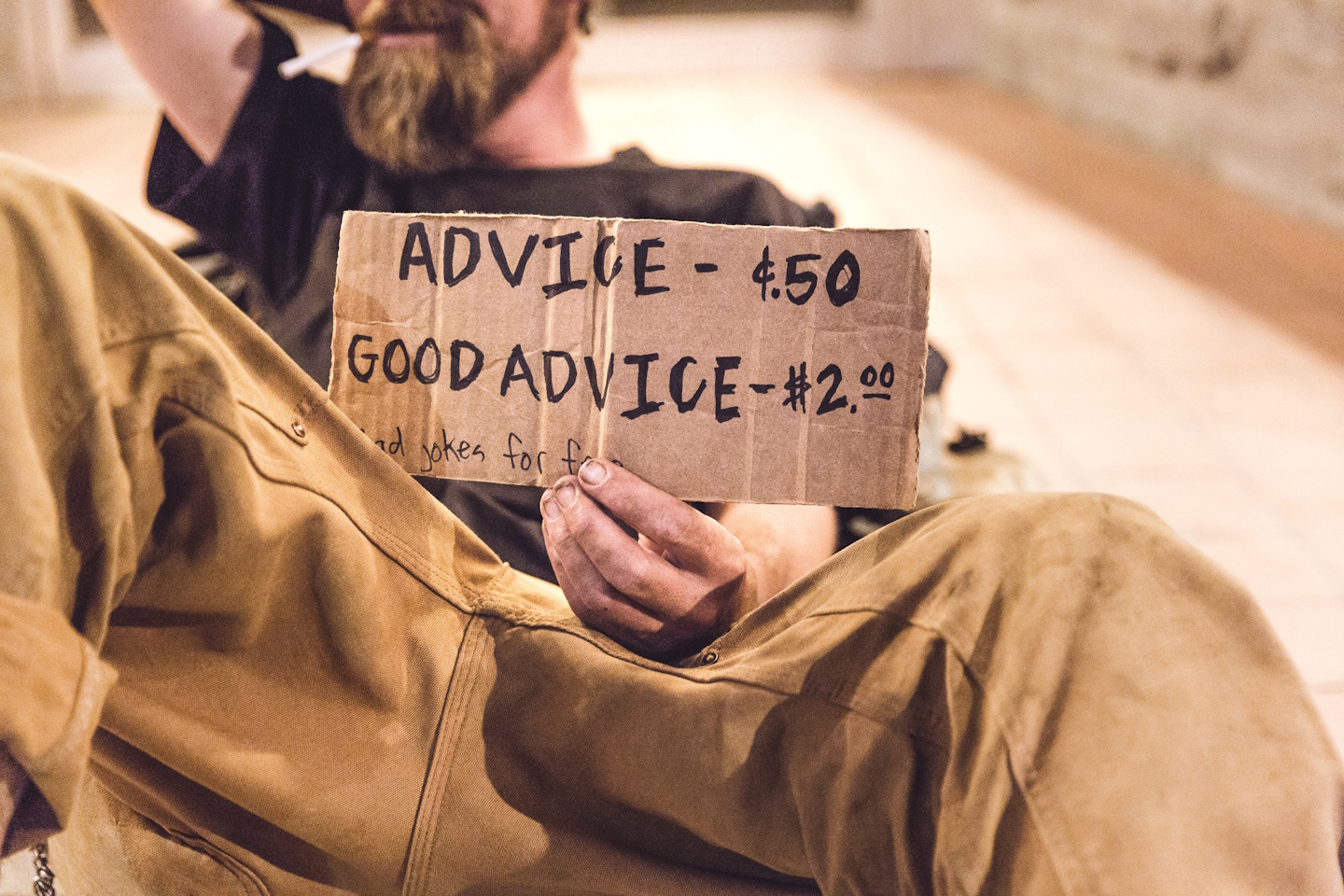Man holding sign saying Advice 50c. Good advice $2.00. Jokes for free