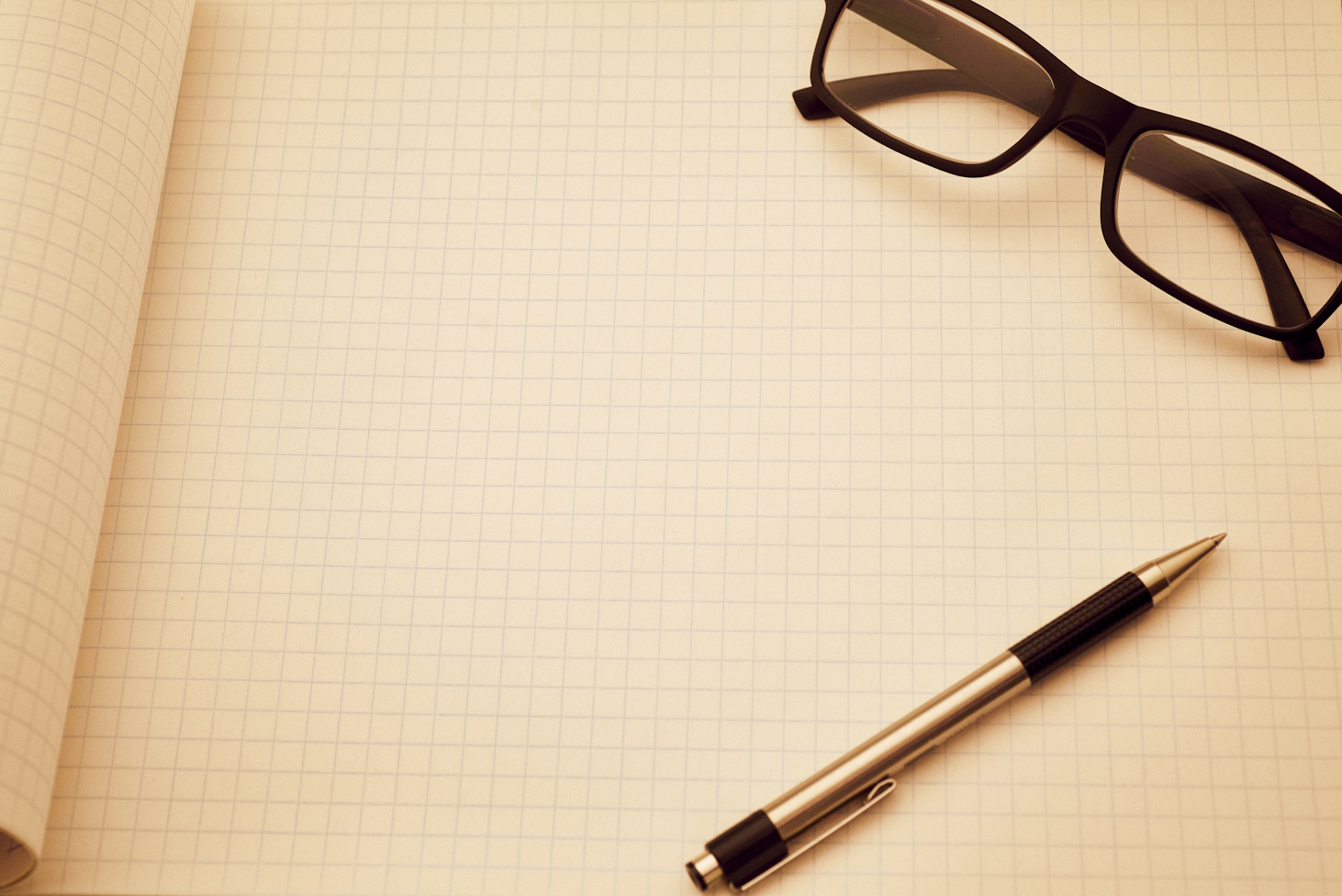 A pen and glasses on blank grid paper