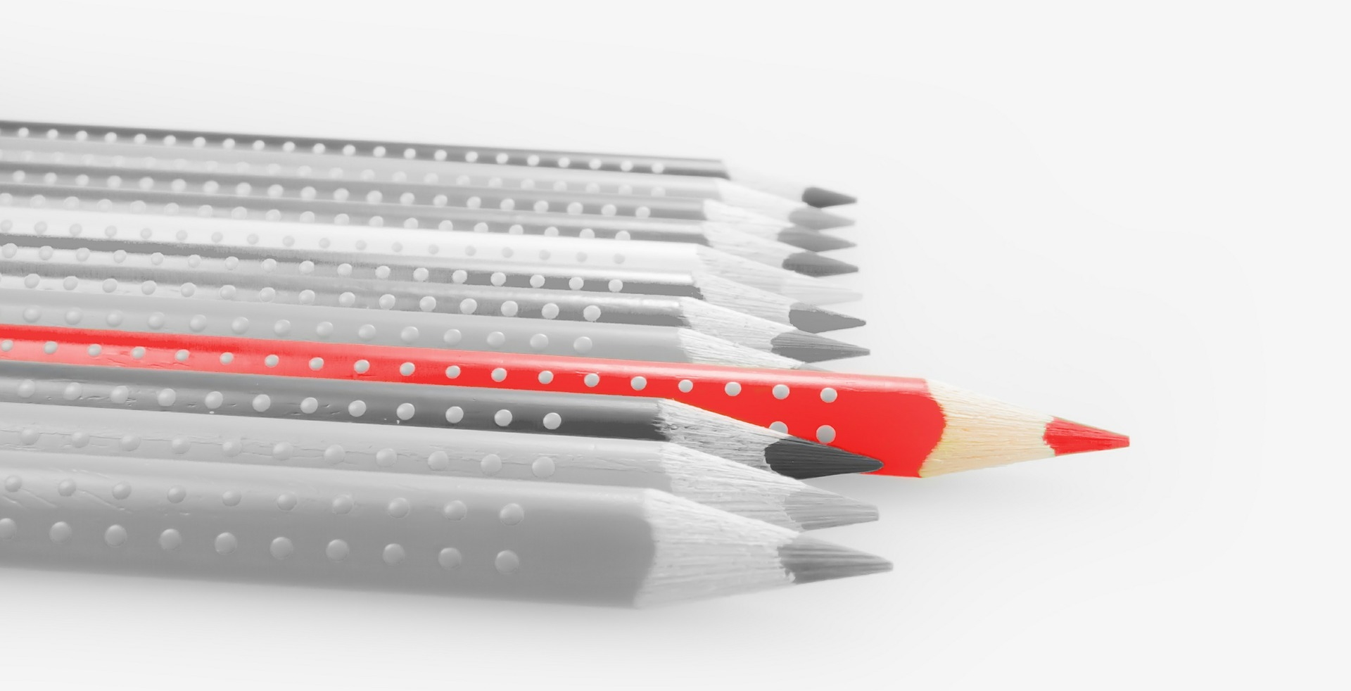 Line of grey pencils with red pencil sticking out