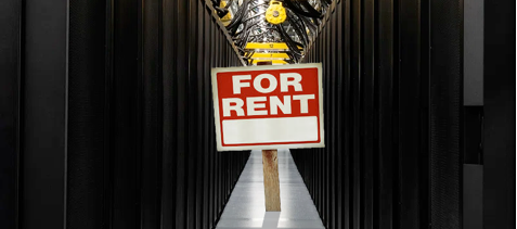 An image showing a datacenter with a yard sign reading "for rent" in the middle.