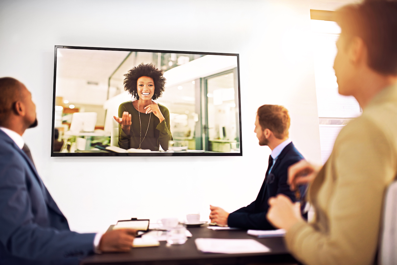 Three people in a conference meeting listening to a remote participant
