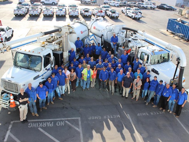 A photo of the employees of SJW standing in front of a fleet of trucks.