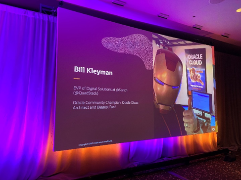 Photo that shows a presentation screen on a stage at an event, with an opening slide for Bill Kleyman's keynote. The slide shows a picture of a man in an Iron Man mask giving a thumbs up sign.